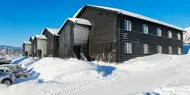 Bilde som viser boligprosjektet Skitorget. Leilighetsbygg som ligger rett ved skibakken. På bildet er det blå himmel og mye flott snø.