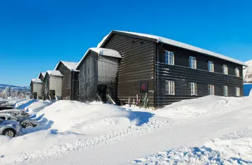 Bilde som viser boligprosjektet Skitorget. Leilighetsbygg som ligger rett ved skibakken. På bildet er det blå himmel og mye flott snø.