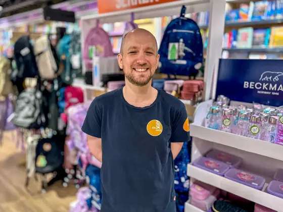 Ansatt fra Ark Bokhandel som smiler i butikken