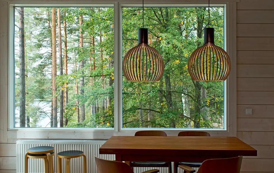 To taklamper i bjørkefiner henger over et spisebord.