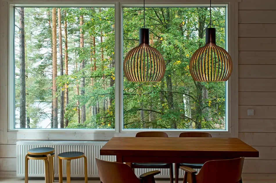To taklamper i bjørkefiner henger over et spisebord.