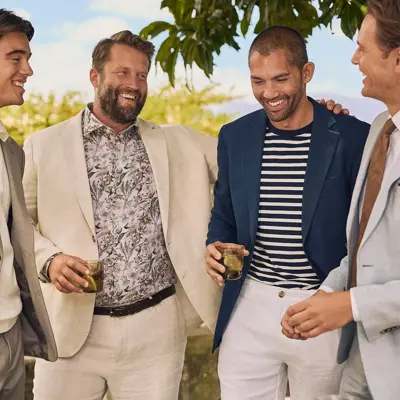 Fem menn står ute i solen med fine klær og ler