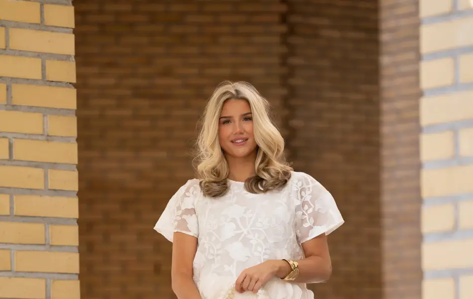 Ung jente med hvit topp og bukse, liten veske og ballerinasko