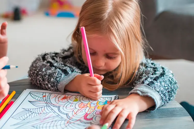 Family colouring books in their living room. They are having fun together.