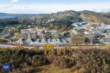 Illustrasjon viser et flyfoto av eksisterende Åsane sentrum, hvor nye planlagte bygninger er tegnet inn i grønt.