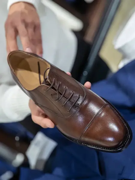 Bilde av hender som holder en brun herresko