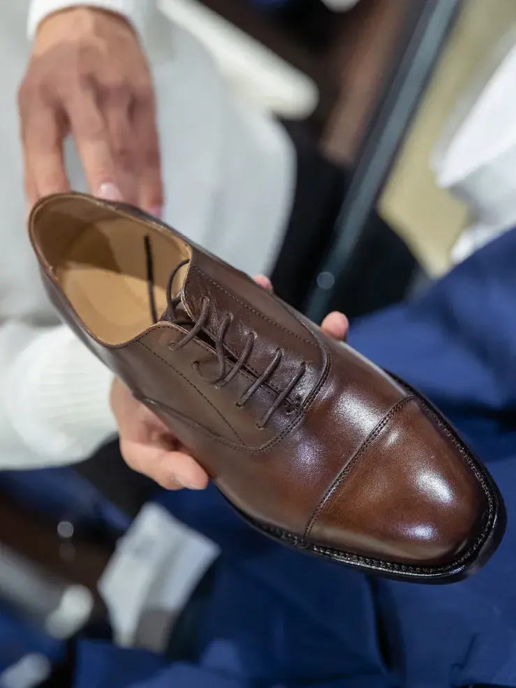 Bilde av hender som holder en brun herresko