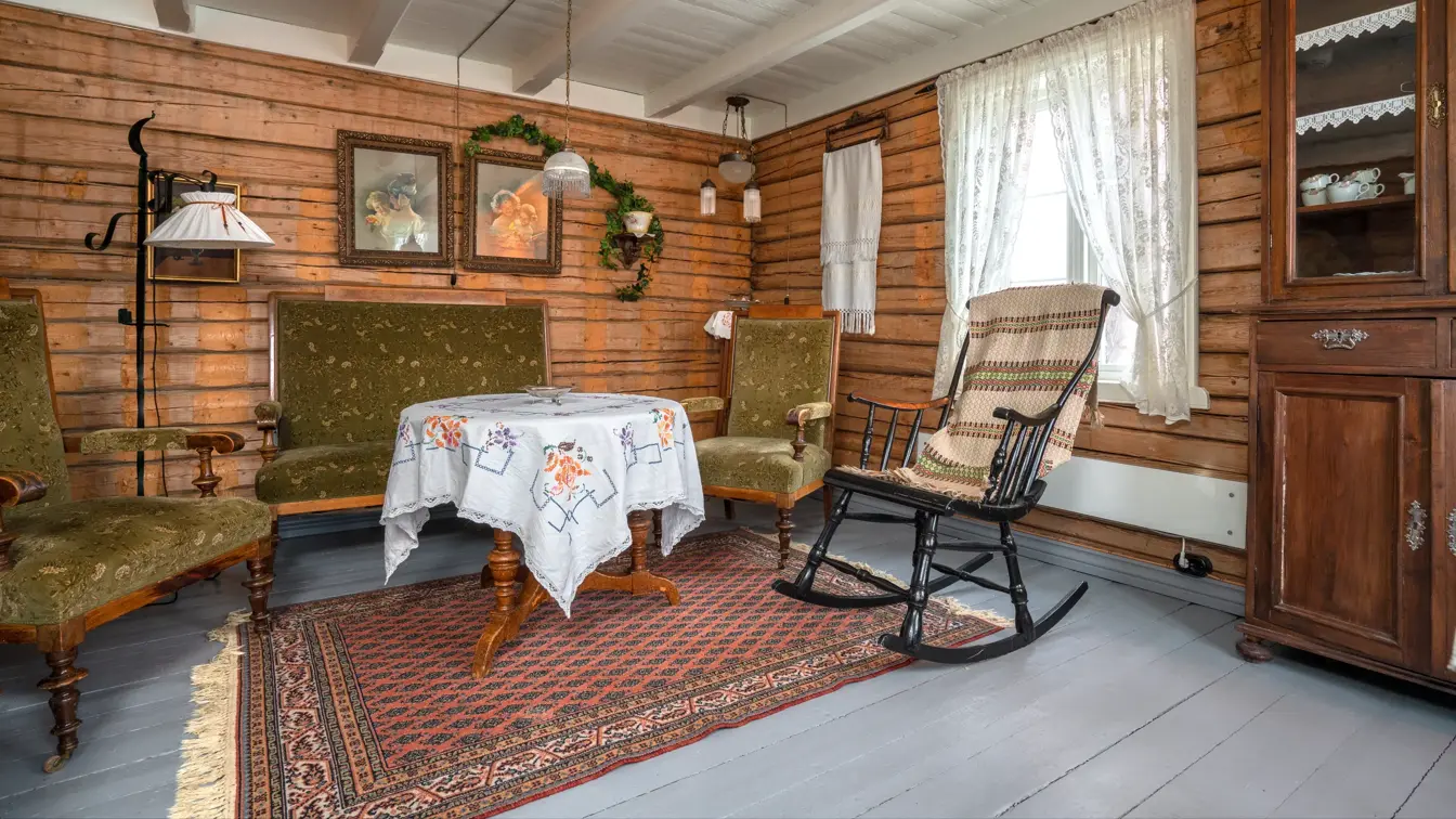 Stuen er innredet med sofa, stoler og bord som står i stil med bygget. Gulv, vegger og tak er av tre.