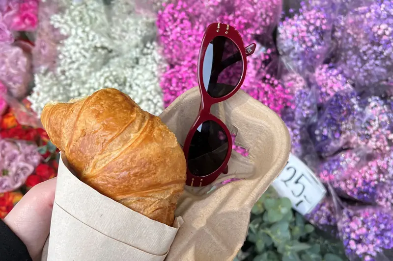 Noen som holder solbriller, en croissant med blomster i bakgrunn