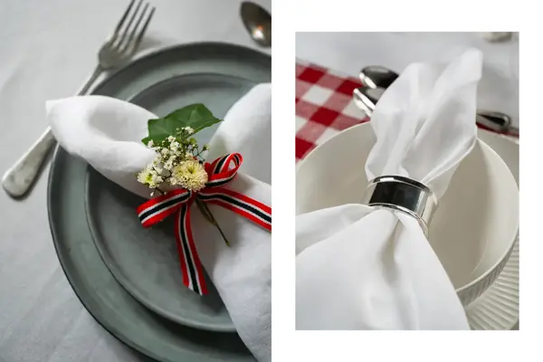 Nærbilde av hvit linserviett med bånd og blomster på en grå tallerken. Hvit linserviett med sølvfarget serveiettring på hvit skål.