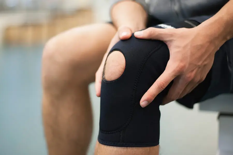 Nærbilde av kneet til en mann som holder på hver sin side av kneet sitt, som har knestøtte på