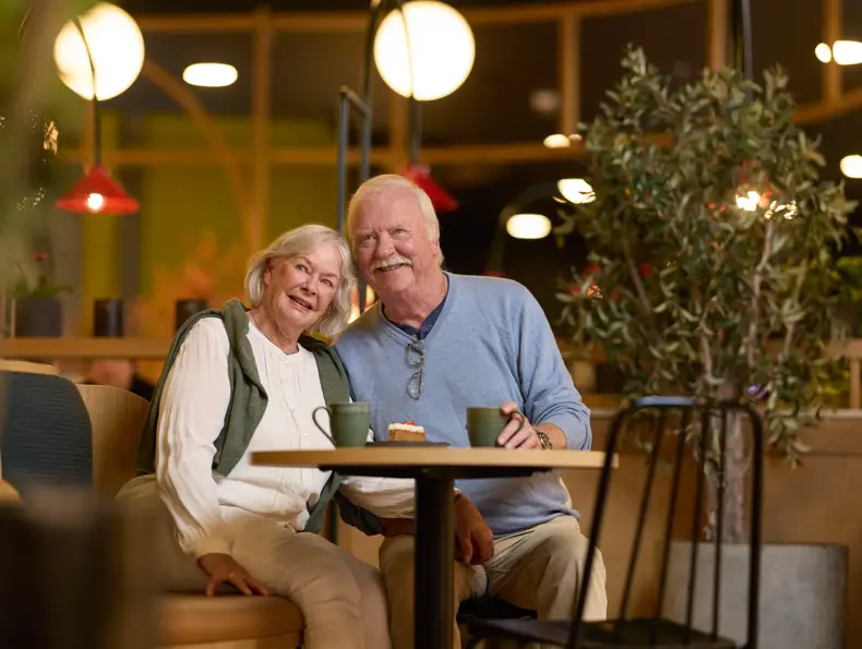 Eldre par, mann og dame, som sitter på cafe. 