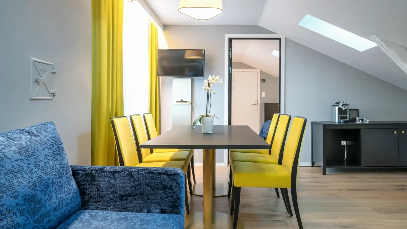 Sofa og spisebord med seks sitteplasser med sikt inn til soverommet på suite på Thon Hotel Spectrum i Oslo sentrum