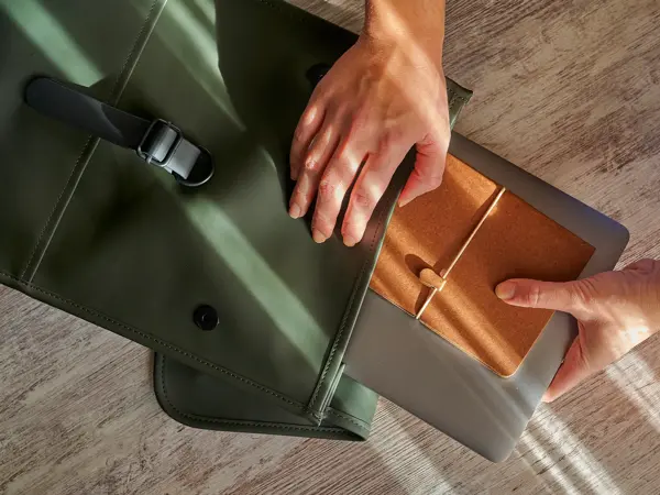 Hands of a woman prepare her office supplies in a backpack
