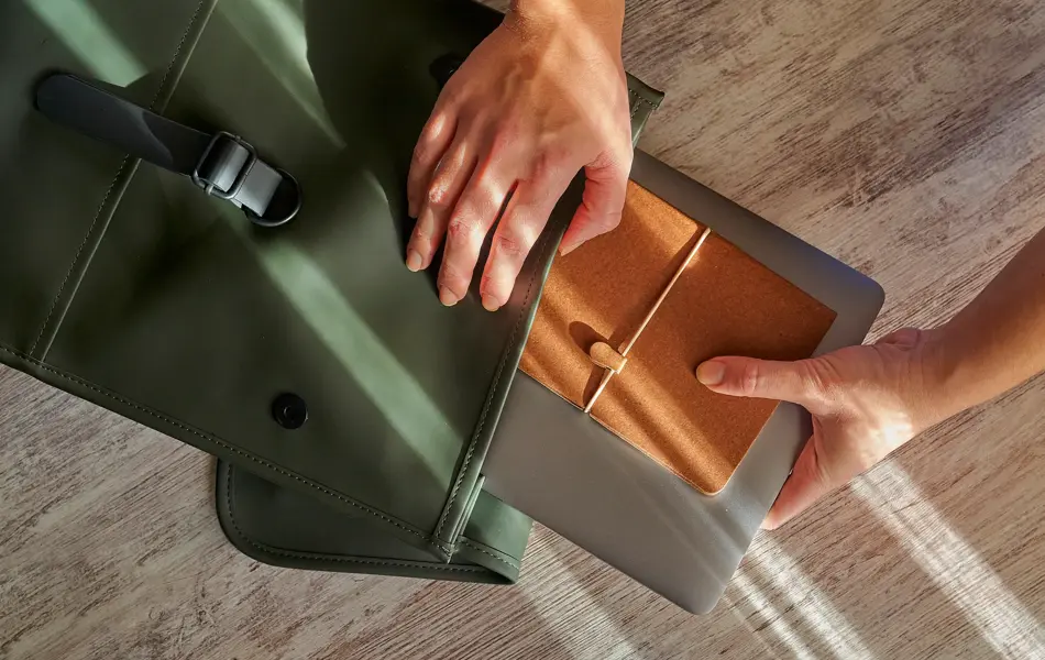 Hands of a woman prepare her office supplies in a backpack