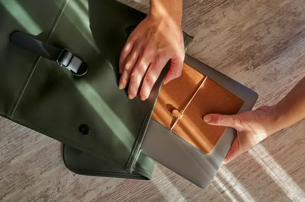 Hands of a woman prepare her office supplies in a backpack