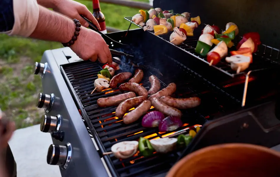 Chef cooking sausages and vegetables on skewers outdoors