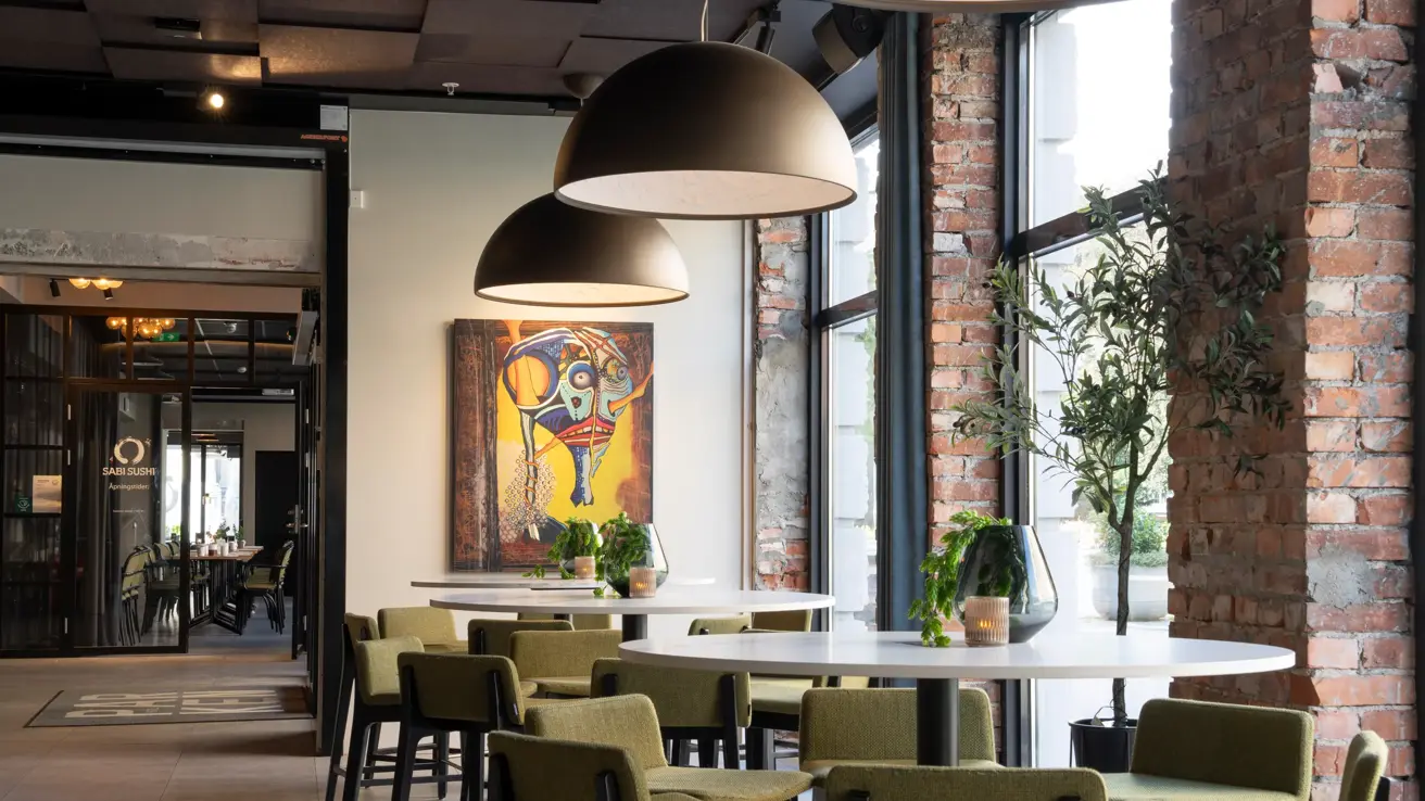 Lounge i rustikk stil med flere runde høybord og høye stoler rundt. 