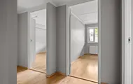 Utsikt gjennom åpne dører til to tomme rom med lyst tregulv, leilighet H0104, Hallingtunet i Flå.