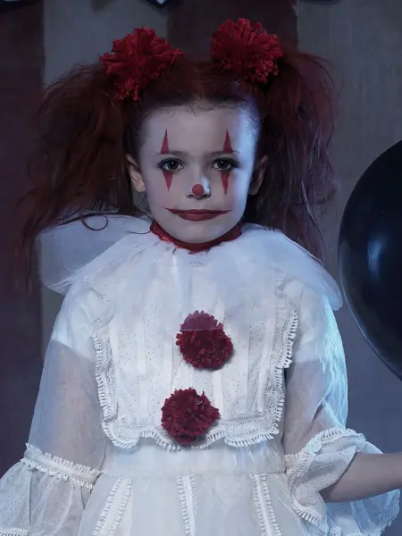 barn kledd ut i hvit kjole, rødt hår og ansiktsmaling