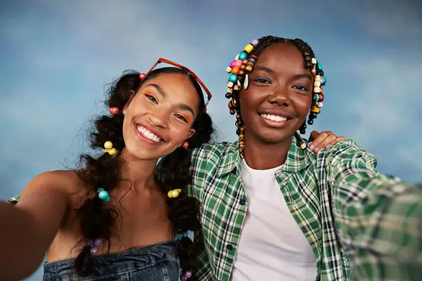 Portrett av smilende multirasiale kvinnelige venner som tar selfie mot farget bakgrunn