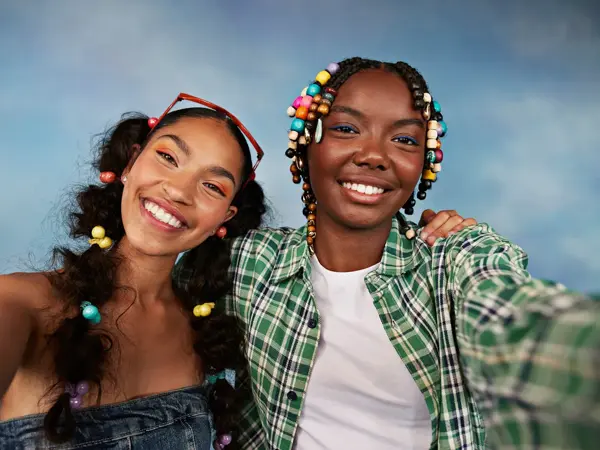 Portrett av smilende multirasiale kvinnelige venner som tar selfie mot farget bakgrunn