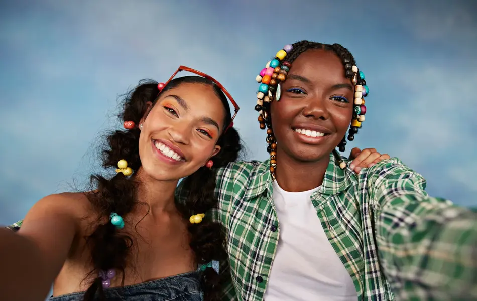Portrett av smilende multirasiale kvinnelige venner som tar selfie mot farget bakgrunn