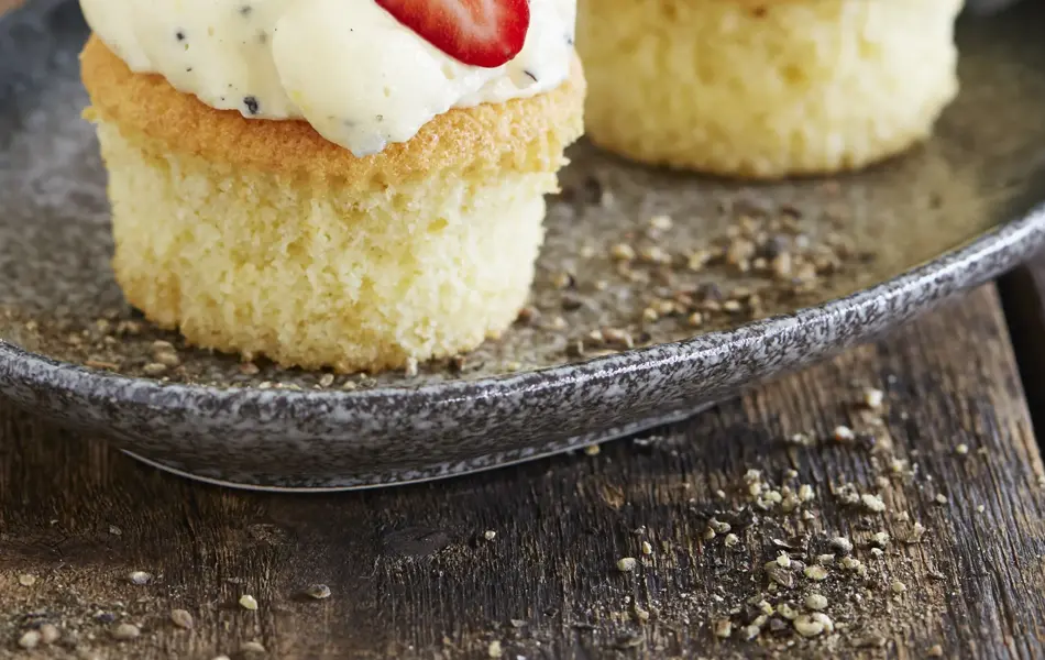 To lyse cupcakes med topping og et halvt jordbær på hver