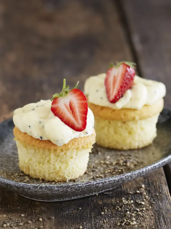 To lyse cupcakes med topping og et halvt jordbær på hver