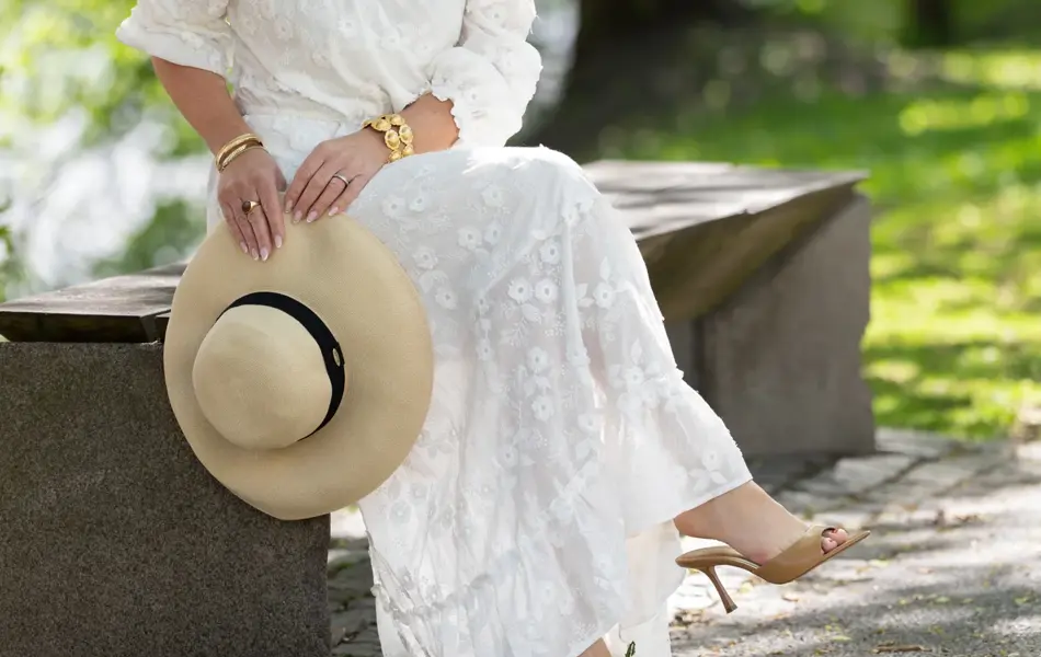 Dame i hvit lang kjole, stråhatt og sandaler