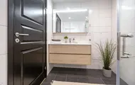 Bildet viser visningsleilighet på Høyfjellstunet på Skeikampen. Badet på bilde har mørkegråe fliser på gulvet, hvite fliser på veggene, speil, dusjhjørne med glassvegger og lyst tre på servantskapet.
