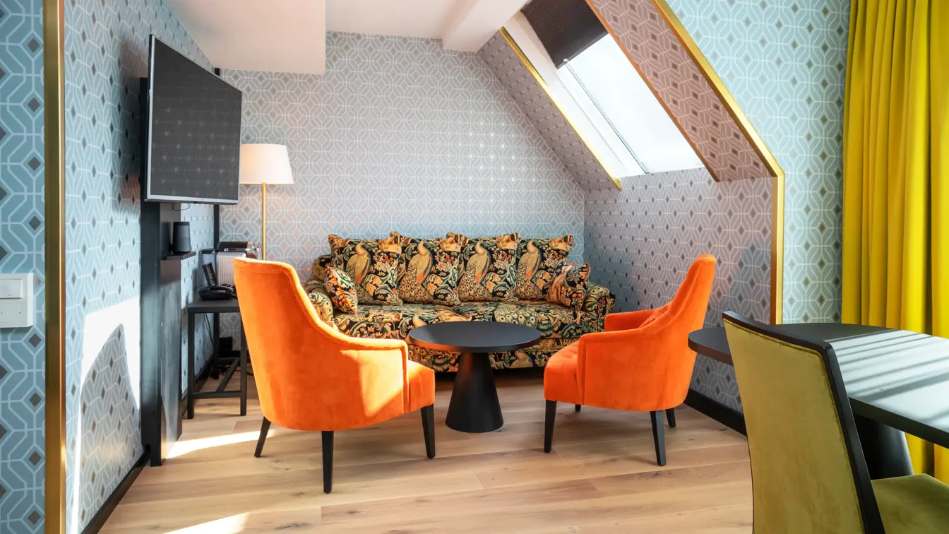 Sittegruppe med to enkeltstoler, tv, store gule gardiner på business room på Thon Hotel Cecil i Oslo sentrum