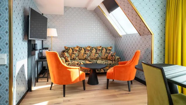 Sittegruppe med to enkeltstoler, tv, store gule gardiner på business room på Thon Hotel Cecil i Oslo sentrum