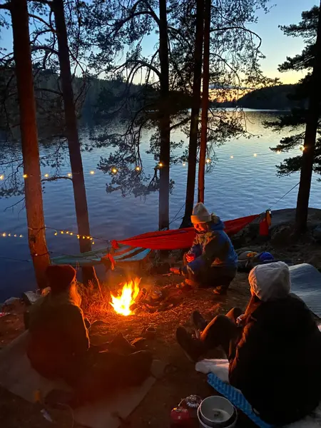 Venner på tur i skogen med bål og lyslenker i mørket