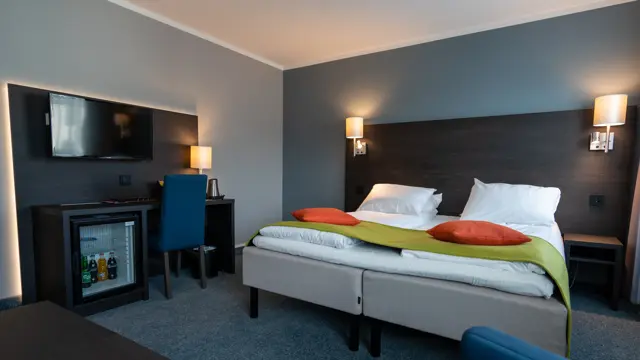 Dobbeltseng, minibar, TV, salongbord, blå lenestol