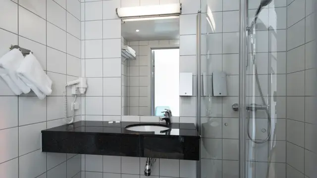Bad med speil, vask, dusjhjørne og håndkler
