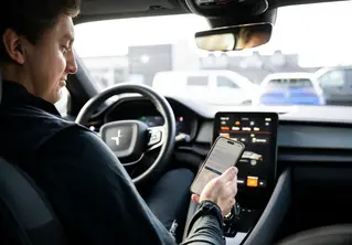 En hånd som holder en mobil i en bil 