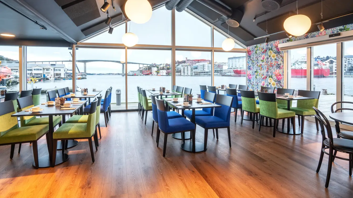 Restaurant, vindu, utsikt mot vannet, grønne og blå stoler, spisebord, parkettgulv, blomstertapet