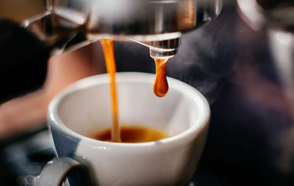Fresh espresso shot pouring out of machine.