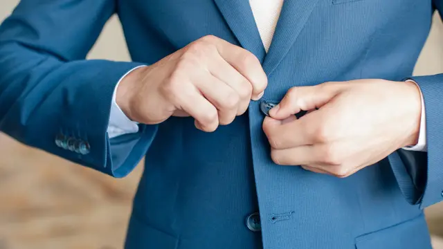 Nærbilde av hender som knepper igjen blazer