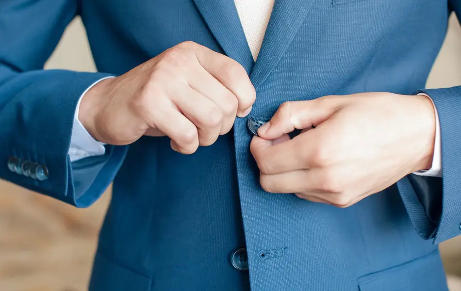 Nærbilde av hender som knepper igjen blazer