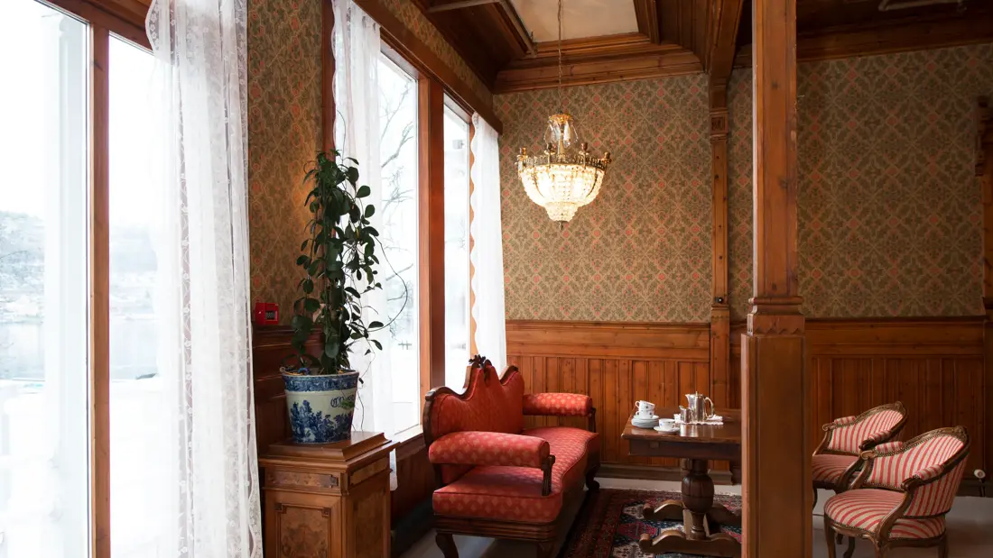 Damesalongen med sofa, stoler, lysekroner og tresøyler på Thon Hotel Sandven