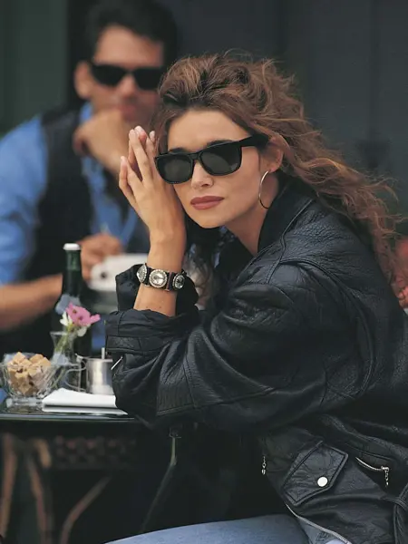 Dame med skinnjakke sitter ved kafébord 