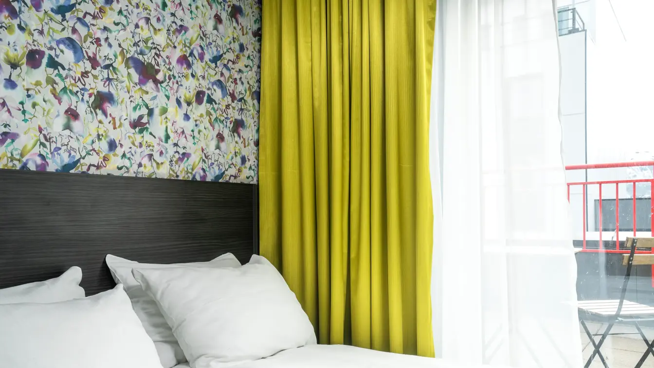 Gule gardiner, dobbeltseng, blomstertapet, vindu.