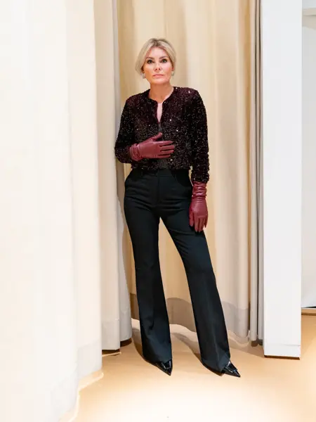 Dame med sort topp, sort bukse, sorte pumps og burgunder skinnhansker.