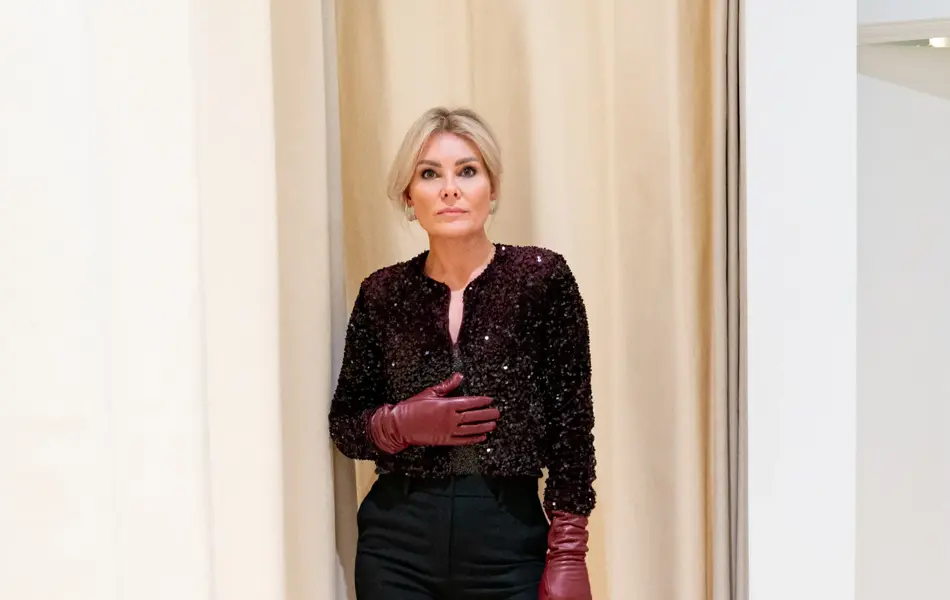 Dame med sort topp, sort bukse, sorte pumps og burgunder skinnhansker.