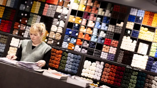 Dame i butikk som ser på strikkeoppskrifter