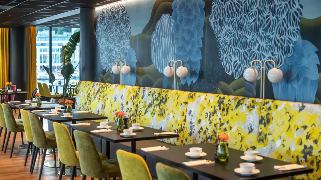 Tapetvegg i mønster, spisebord, grønn stol, gul sofa 