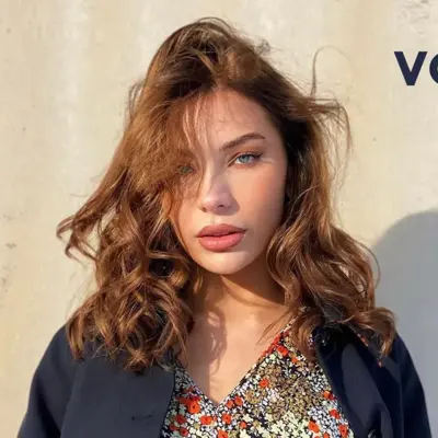 Dame med blomstrete kjole og blå blazer. Tekst: Vaag