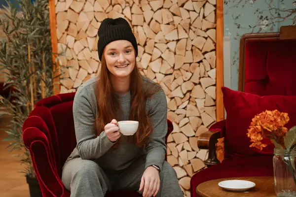 blid ansatt viser frem grå kosedress